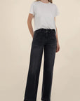 Person wearing a white t-shirt and black jeans on a beige background