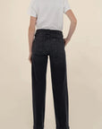 Person wearing black jeans and a white shirt on a beige background