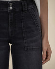 Black denim jeans worn by a person on a beige background