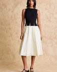 Woman wearing a black and white dress against a beige background