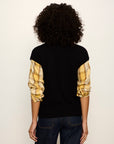 Person wearing a black sweater with yellow plaid sleeves on a white background