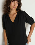 Woman wearing a black top with short sleeves against a white background