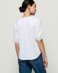 Person wearing a white blouse and blue jeans against a plain background