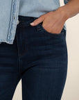 Person wearing dark blue jeans and a light blue denim shirt against a neutral background