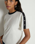 Woman wearing a white t-shirt with black accents on a plain background
