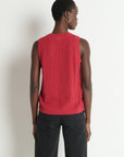 Person wearing a red sleeveless knitted top against a white background