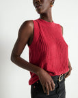 Woman wearing a red knitted sleeveless top against a white background