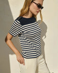Woman wearing a striped shirt and sunglasses against a neutral background