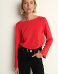 Woman wearing a red sweater and black pants against a white background