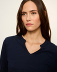 Woman wearing a navy blue top against a plain background