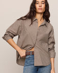 Woman wearing a brown checkered shirt and blue jeans on a beige background