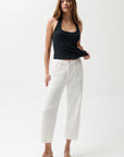 Woman wearing a black tank top and white pants on a white background