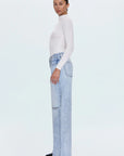 Woman wearing a white turtleneck and light blue jeans on a white background