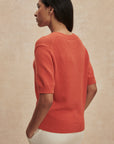 Woman wearing a red sweater against a beige background
