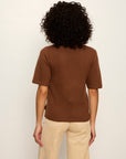 Person wearing a brown sweater and beige pants against a white background
