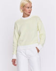 Person wearing a light green sweater and white pants on a white background