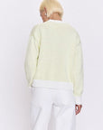 Person wearing a light green striped sweater and white pants on a white background