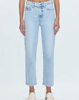 A pair of high-waisted, straight leg blue jeans with a cropped hem, paired with white shoes.
