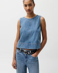 Woman wearing a denim sleeveless top and jeans on a plain background