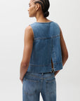 Person wearing a denim vest and jeans on a plain background