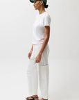 Person wearing a white t-shirt and pants with a green cap on a white background