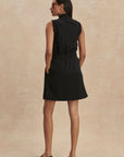 Woman wearing a black sleeveless dress against a beige background