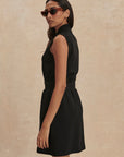 Woman wearing a black sleeveless dress against a beige background