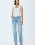 Woman wearing a white tank top and light blue jeans on a white background