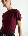 Woman wearing a burgundy top with a plain background