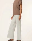 Person wearing a brown t-shirt and light gray pants on a white background
