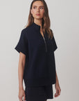 Woman wearing a navy blue outfit with a plain background