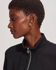 Woman wearing a black jacket with a zipper, side view