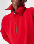 Person wearing a red quarter-zip sweatshirt on a light gray background