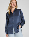 Woman wearing a navy blue shirt and light blue jeans against a gray background