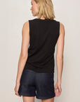 Woman wearing a black sleeveless top and dark shorts on a plain background