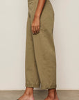 Person wearing olive green pants with a neutral background