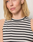 Woman wearing a black and white striped sleeveless top against a plain background