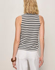Woman wearing a black and white striped sleeveless top with white pants on a plain background