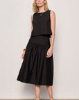 Woman wearing a black sleeveless top and skirt against a plain background