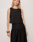 Woman wearing a black sleeveless top and skirt against a plain background