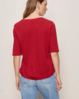 Woman wearing a red shirt and blue jeans on a plain background