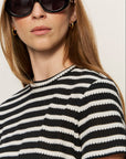 Person wearing black and white striped shirt with sunglasses and earrings
