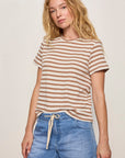 Woman wearing a striped shirt and denim shorts against a plain background