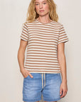 Woman wearing a striped shirt and denim shorts against a plain background