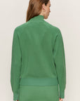 Woman wearing a green outfit against a plain background