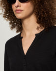 Person wearing a black shirt and sunglasses with a neutral background