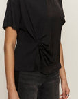 Black top with a knot detail worn by a person on a plain background