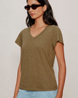 Woman wearing a green t-shirt and sunglasses against a plain background