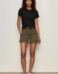 Woman wearing a black t-shirt and green shorts against a plain background