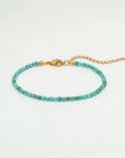 Turquoise beaded bracelet with gold clasp on a white background